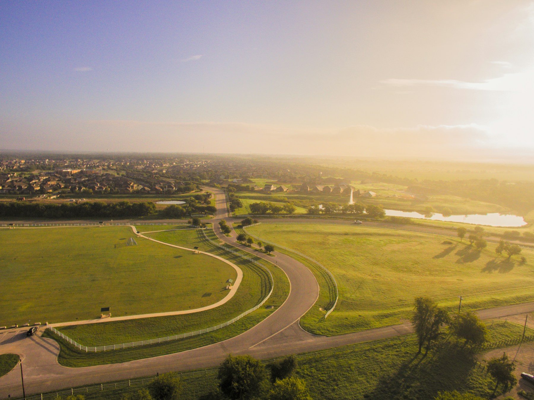 Curving roads connecting open green land and neighborhoods in San Marcos, Central Texas