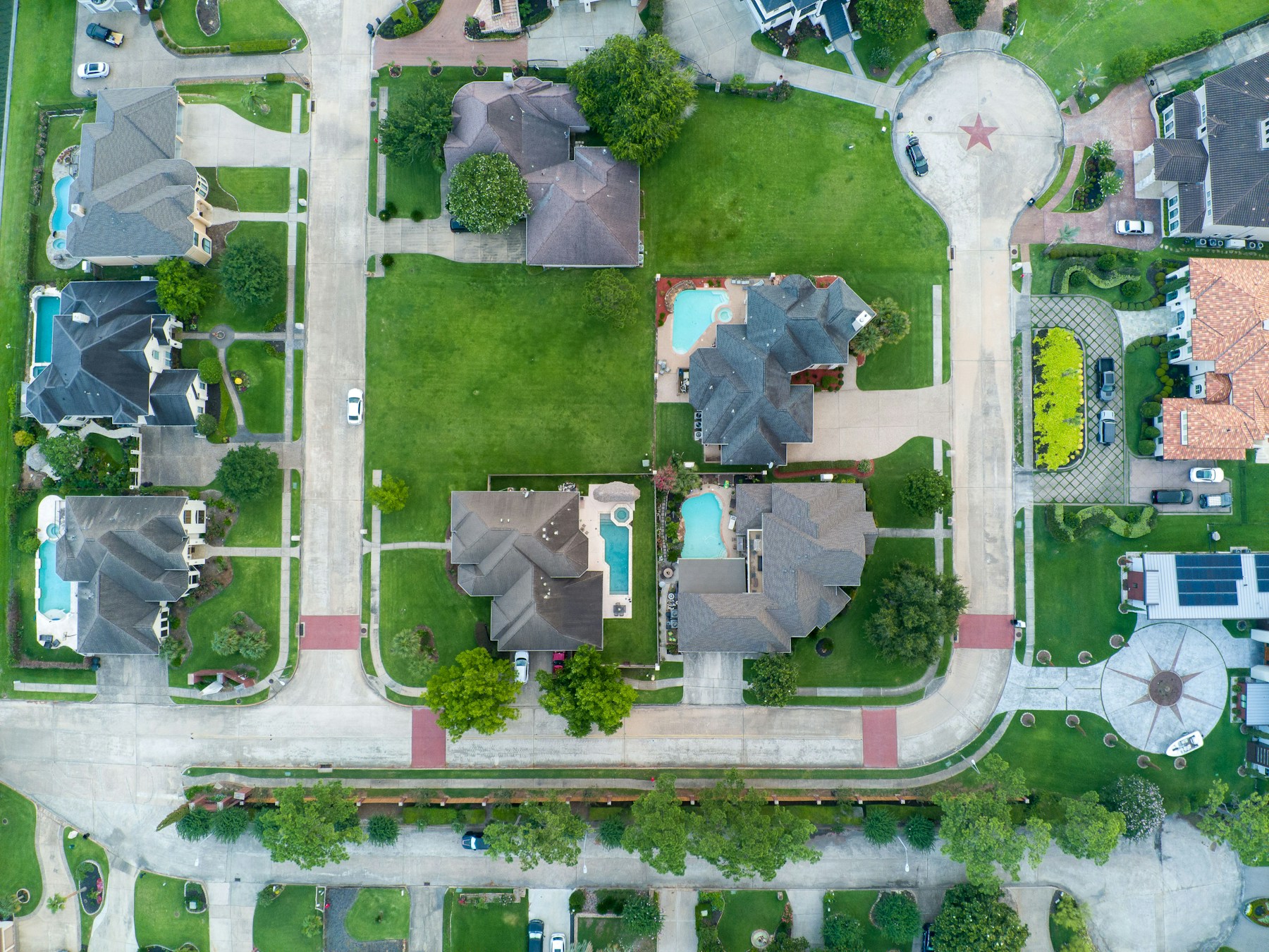 Overhead view of homes, green lots, sidewalks, and connected neighborhood streets in Texas